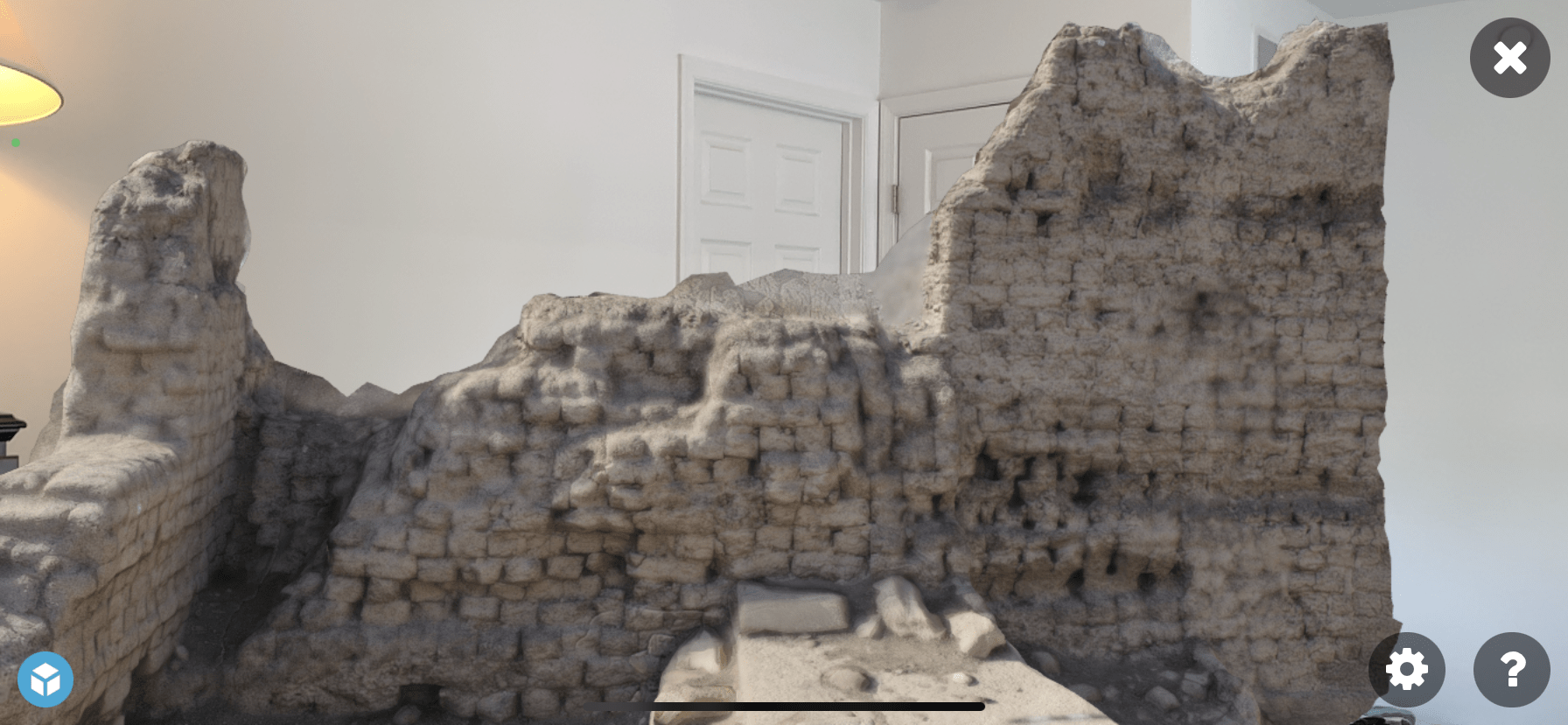 A rendering of a close up of the Western High Gate of Medinet Habu, as it would be displayed in augmented reality, showing a the model overlaid in a camera view of the inside of an apartment. 