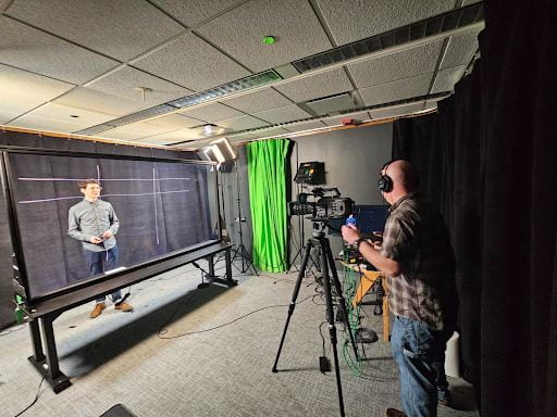 Aidan Kaplan, Assistant Instructional Professor of Arabic, is drawing a chart on the lightboard while Andy Poulos, Multimedia Specialist, checks the settings of the video in the studio. Photo by Academic Technology Solutions. 
